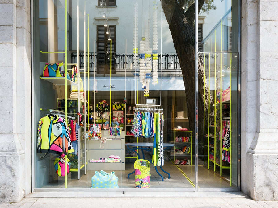 Das Schaufenster des Temporary Stores in Riccione mit limettengrünen Stangen und bunten Badeanzügen