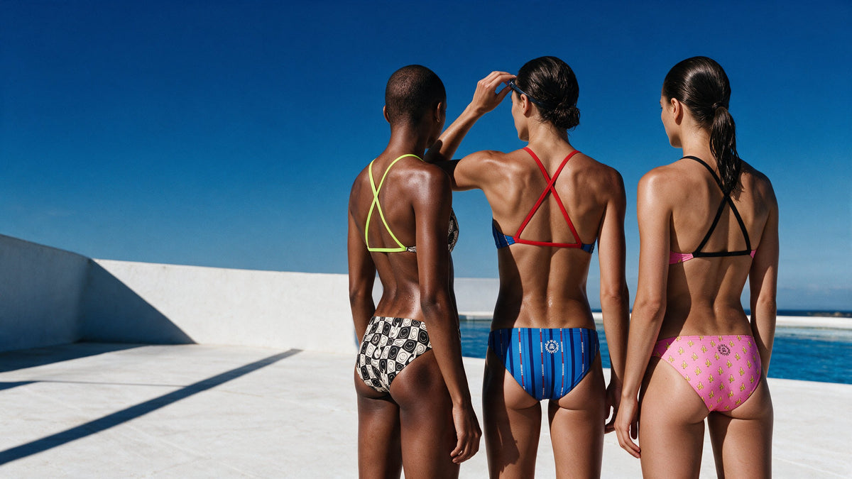 Three swimmers seen from behind in BONESWIMMER Maui training bikinis at the pool